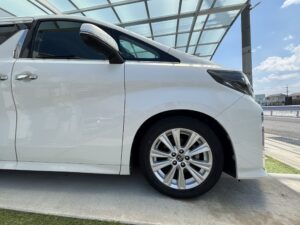 白い30系後期アルファードの運転席側前方と純正アルミホイールの外観