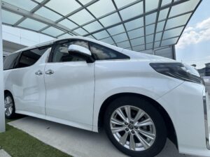 カーポートに駐車した白い30系後期アルファードの運転席側外観